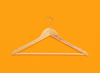 Clothes hanger on a bright orange background. Yellow background with copy space. Empty clothes hanger, store and wardrobe accessories. Bright fashion shopping concept