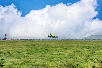 Fototapeta premium A big yellow jet taking off from the airport on background of cloudy blue sky.