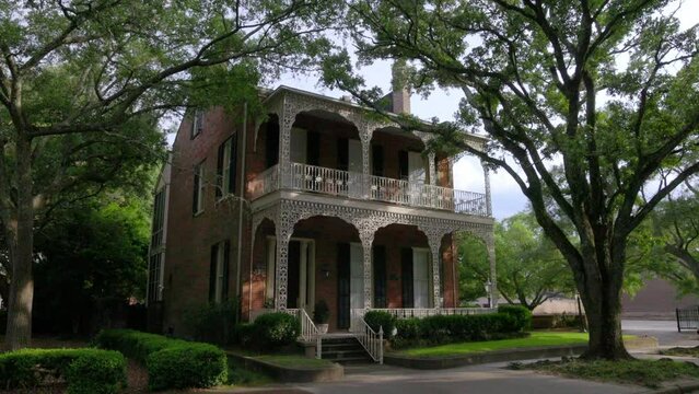 Historic home with iron fence and old Southern Live Oak trees in downtown Mobile, Alabama with gimbal video walking forward at an angle.