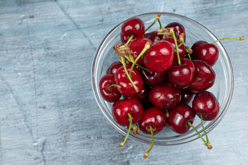 Cherries in the bowl isolated above blue background with copy space