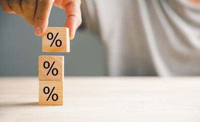 Concept of interest rate and financial rates. Hand placing a wooden cube block on top, symbolizing an increasing trend, with an upward direction icon and percentage symbol. - obrazy, fototapety, plakaty