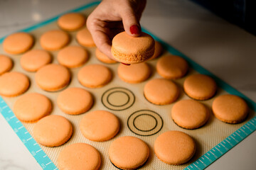 Woman's hands gently holds connected together two halves of macaroons. Close-up.
