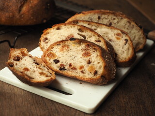 slice of raisin, cranberry and perilla seed bread on white cutting board