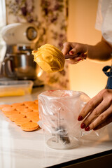 Woman confectioner fills confectionery bag with freshly prepared cream, closeup view. Blurred background