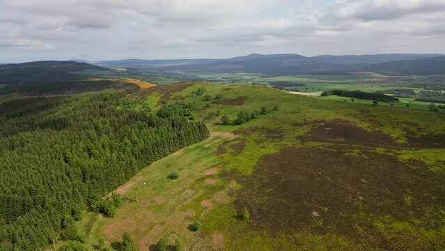 Forward rising aerial of green hill, forest and valley in Scotland