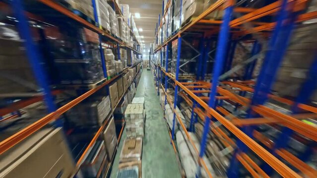 FPV drone shot in middle of warehouse shelfs full of plastic foil wrapped goods