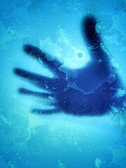hand silhouette on broken glass blue background