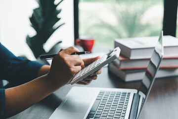 Young woman of banking finance officer using computer laptop and use calculator. Business woman holding pen in her hand using and internet connection for the communication service as a professionally.