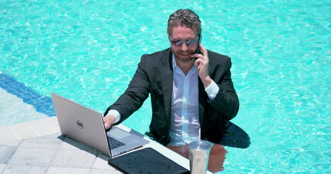 Businessman in suit with laptop in swimming pool. Crazy business man on summer vacation. Excited businessman in wet suit in swim pool. Funny business man, comic business. Remote online working.