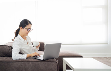 asian mature woman working on laptop in living room at home office. asian professor  using computer remote teaching , virtual training, e-learning, watching online education webinar at home
