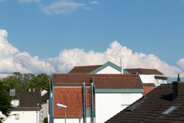 Ciel bleu et nuages blancs au-dessus de maisons aux toits en tuile rouges et verts 