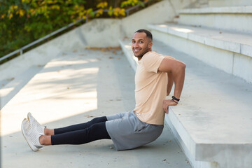 Fototapeta na wymiar Successful hispanic sportsman doing various physical exercises, morning workout at the stadium, man motivationally smiling and looking at the camera, athlete in the air fitness.