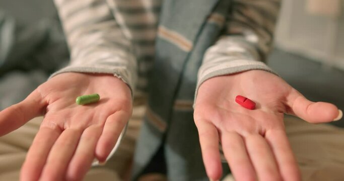 female offers pill medicine or drugs woman opens fist to reveal pill in palm. woman in striped sweater scarf offer a choice two opposite colorful pills. decision making or temptation. Close-up cropped