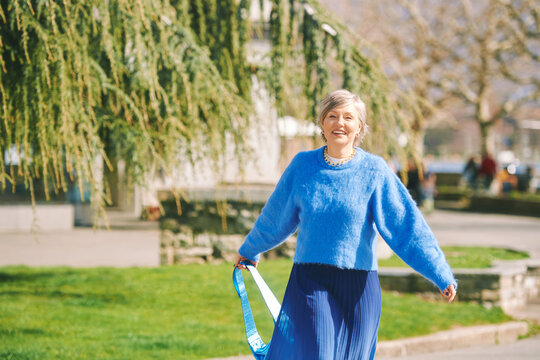 Outdoor Portrait Of Happy Mature Woman Walking Down The Street On A Nice Sunny Day, Wearing Blue Clothes