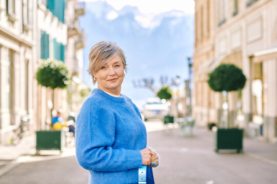 Outdoor portrait of beautiful middle age 55 - 60 year old woman posing outside, wearing blue pullover