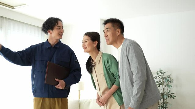 作業着を着た日本人男性とシニアの日本人夫婦