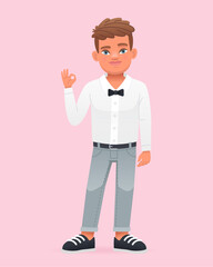 A cheerful little boy shows an OK sign. A beautiful cute schoolboy child in a white shirt with a bow tie.