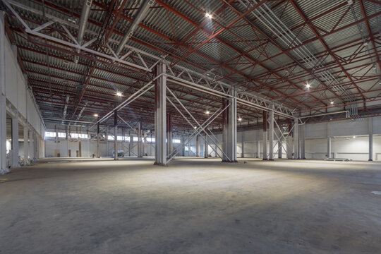 A large modern empty warehouse. Metal bearing structures. Smooth gray floor.