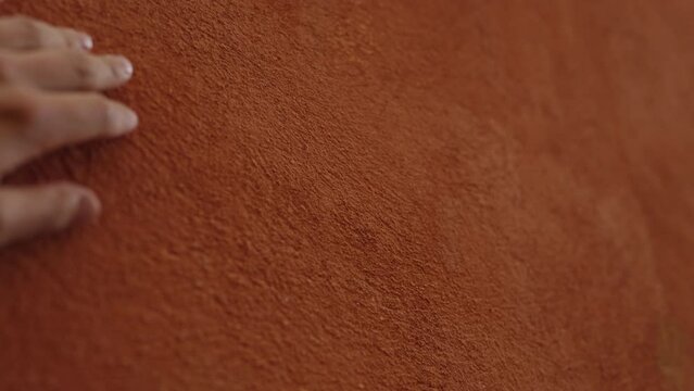 Slow motion man hand touching terracotta wall