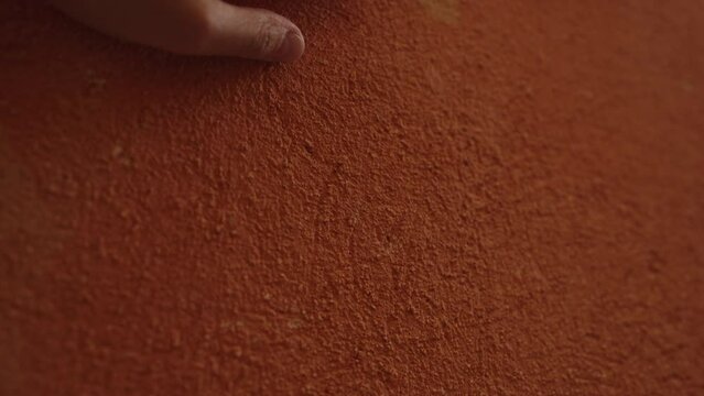 Slow motion man hand touching terracotta wall