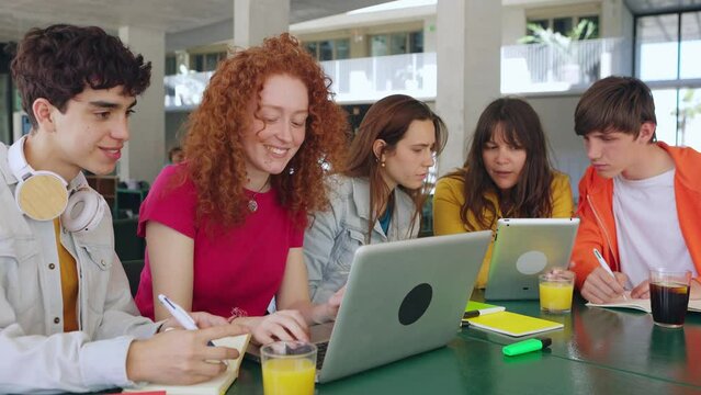 Young students group working with laptop computers at college library. Secondary school classmates studying together preparing exams. Education lifestyle concept.
