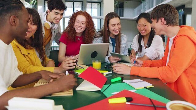 Secondary school students studying together with laptops at high school campus. Multiracial group of men and women classmates working and learning sitting on table preparing final exams. Education.
