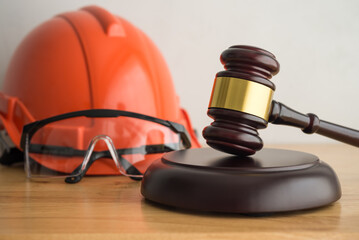 Hammer judge gavel with construction hat helmet, worker safety glasses on wooden background. Labour...