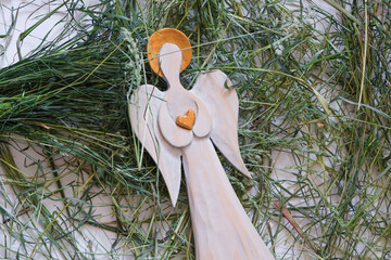 Wooden angel with a golden halo and heart in hands. Green hay. The Apple Feast of the Saviour. 