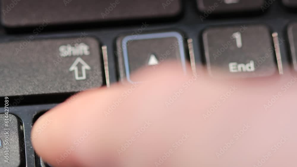 Poster finger presses on the arrow button on the laptop keyboard