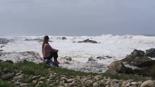 Young woman sitting and meditating on the ocean
