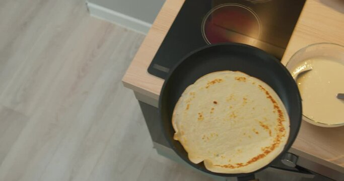 talented skilled chef turning pancakes, closeup top view slow motion man is flipping crepes in the air using a frying pan