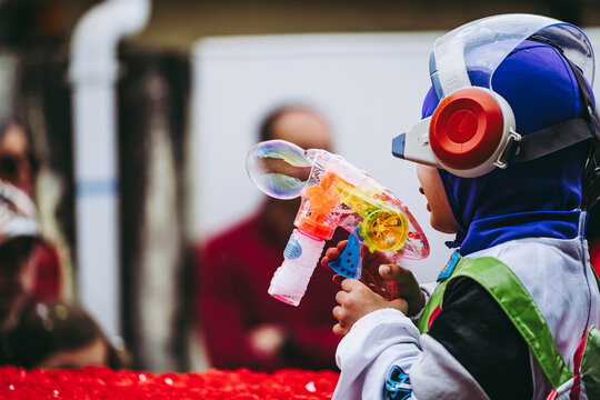 Enfant en train de tirer avec un jouet en plastique color&eacute; pistolet &agrave; bulles