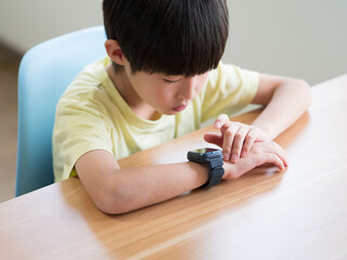 スマートウォッチを操作している小学生の男の子