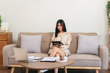 Female entrepreneur is sitting on big comfortable sofa and writi