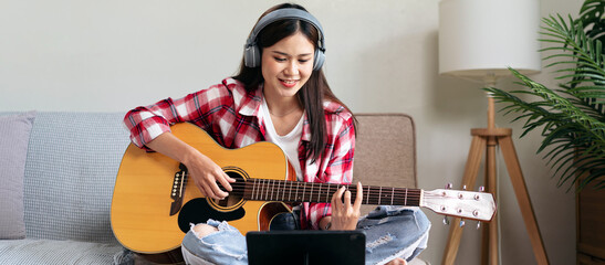 Young woman is playing guitar and practice to singing the song w