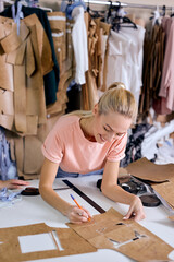 beautiuful caucasian woman at garment factory, preapring textile for work, at modern workshop alone, confident professional seamstress enjoy dressmaking and sewing in textile factory