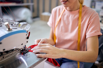 cropped unrecognizable seamstress in factory sewing using modern industrial sewing machine,...