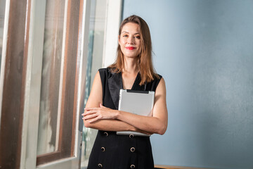 Female secretary smiling happy hugging tablet and holding documents confident in office work