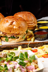Burgers on wood board with french fries and sauces