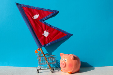 Shopping cart and piggy bank with Nepalese flag. Favorable and economical shopping in Nepal. Cheap...
