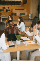 Young, multiracial coworkers discussing profit growth together at modern co working space