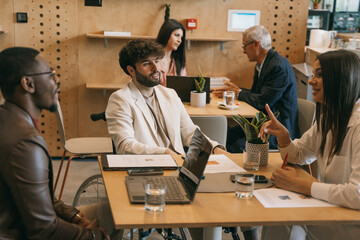 Multiracial, inter-generational businesspeople working at modern co working space. Brunette girl...