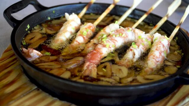 Garlic brochette prawns, in a casserole with boiling oil