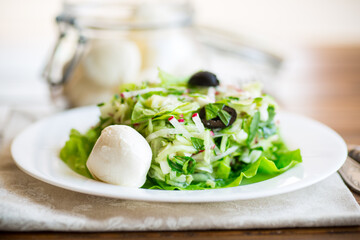fresh summer salad with early cabbage, cucumbers, radishes and other vegetables in a plate