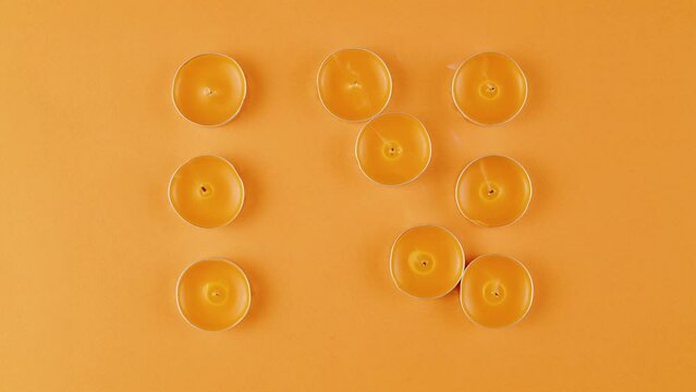 Aroma candles with glitter sprinkles on orange background close up top view. Summer bright texture studio shot for spa, shop, supermarket, aromatherapy, products for house, bathroom, meditation.