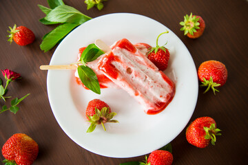 homemade strawberry ice cream on a stick in a plate with strawberries