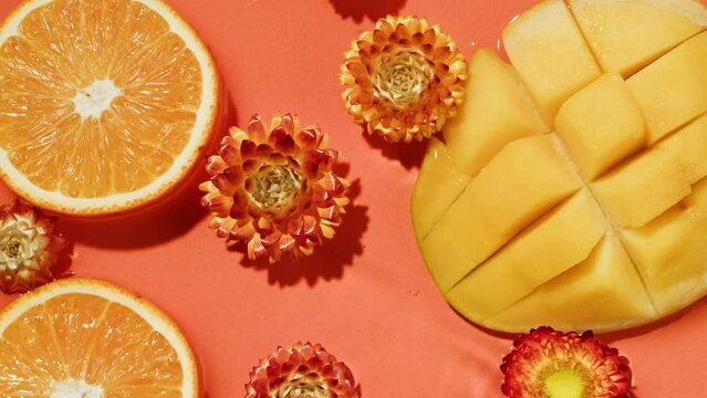 Composition of citruses. dried flowers helichrysum, mango in water on pink background close up, top view. Summer bright texture studio shot for shop, supermarket, spa, cosmetology, restaurant, bar.