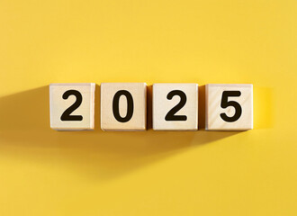 2025 displayed on wooden letter blocks on pastel yellow background