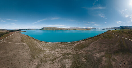 An aerial view of the blue glacial lake - Lake Tekapo, with mountains and blue sky backgrounds, in South Island, New Zealand