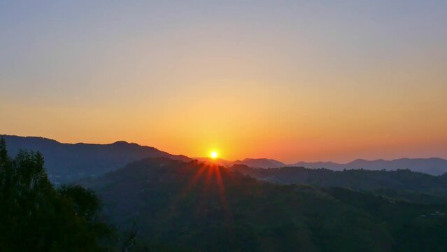Beautiful sunset on the hill amid the mountain range with the setting sun in Chiang Rai..Sunbursts flashed in the mountains range in beautiful sunset..Majestic sunset or sunrise landscape.